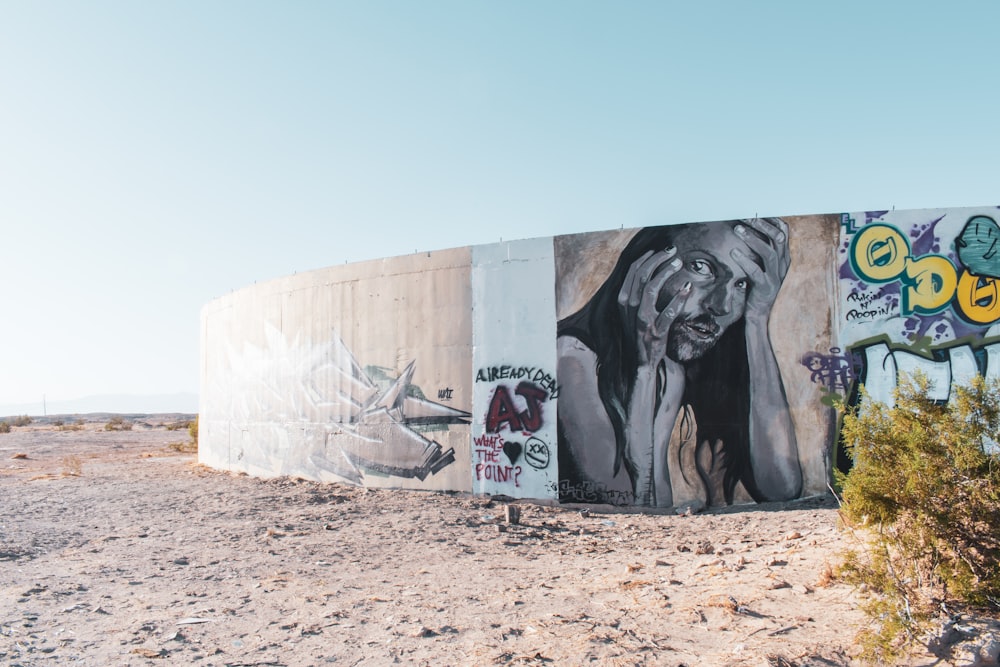 a wall covered in graffiti in the middle of a desert