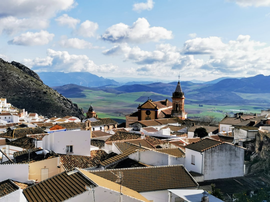 white and brown houses near green mountain under white clouds during daytime