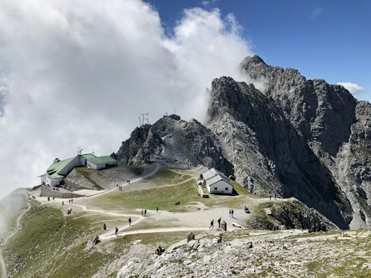 Green and white house on green grass field near rocky mountain under white clouds during daytime — Innsbruck, Austria