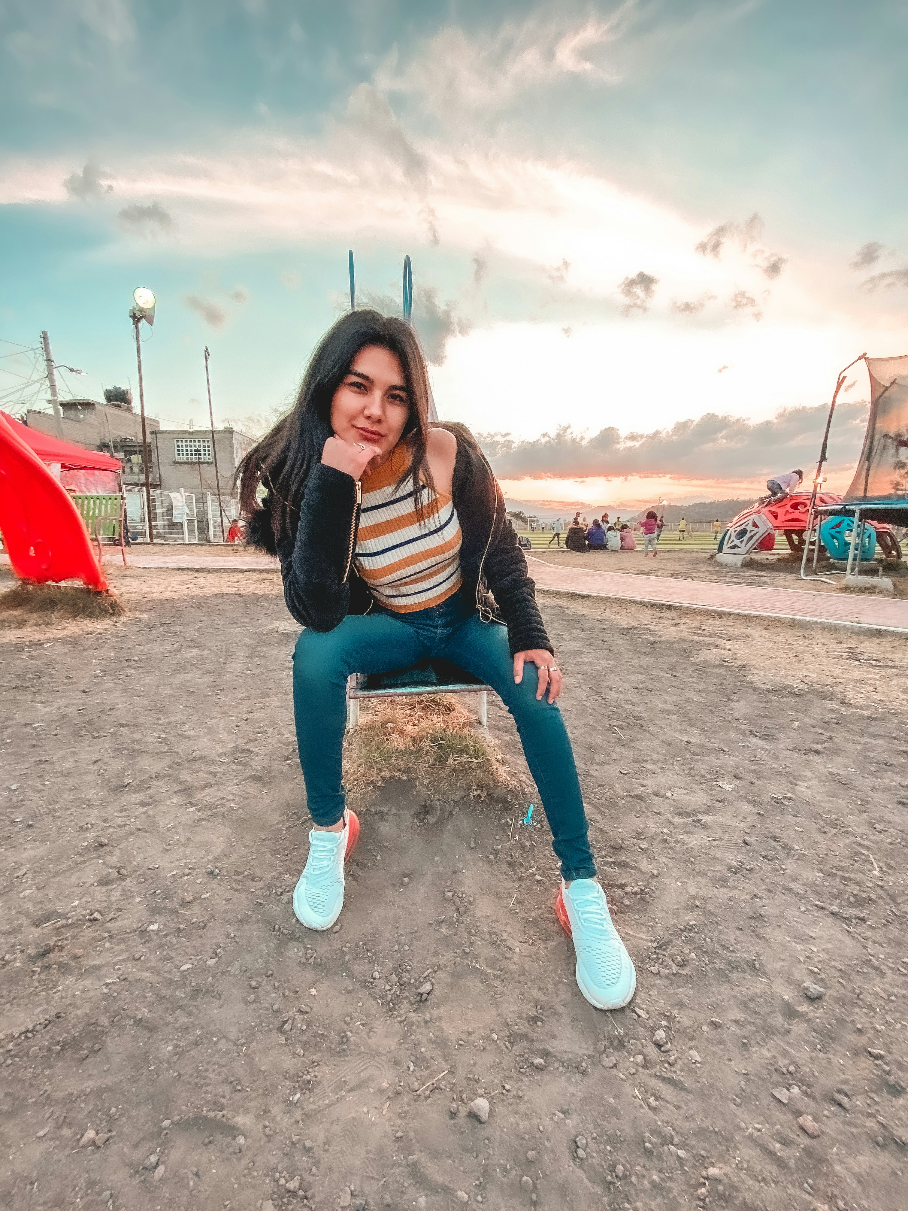 wanita dengan kemeja lengan panjang bergaris hitam dan putih dan jeans denim biru duduk di atas merah
