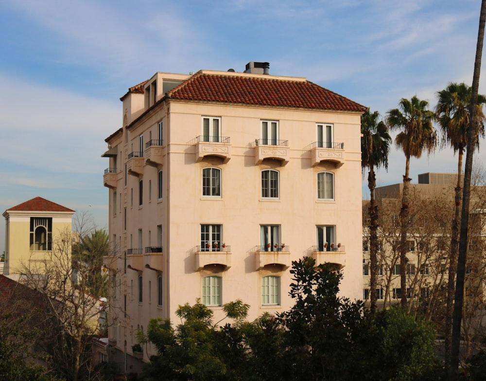 Bâtiment en béton beige près d’arbres verts sous un ciel bleu pendant la journée