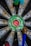 Close-up view of a dartboard with a vibrant green center and surrounding metal segments. Several darts are lodged into the board, suggesting a game in progress or completed.