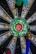 Close-up view of a dartboard with a vibrant green center and surrounding metal segments. Several darts are lodged into the board, suggesting a game in progress or completed.