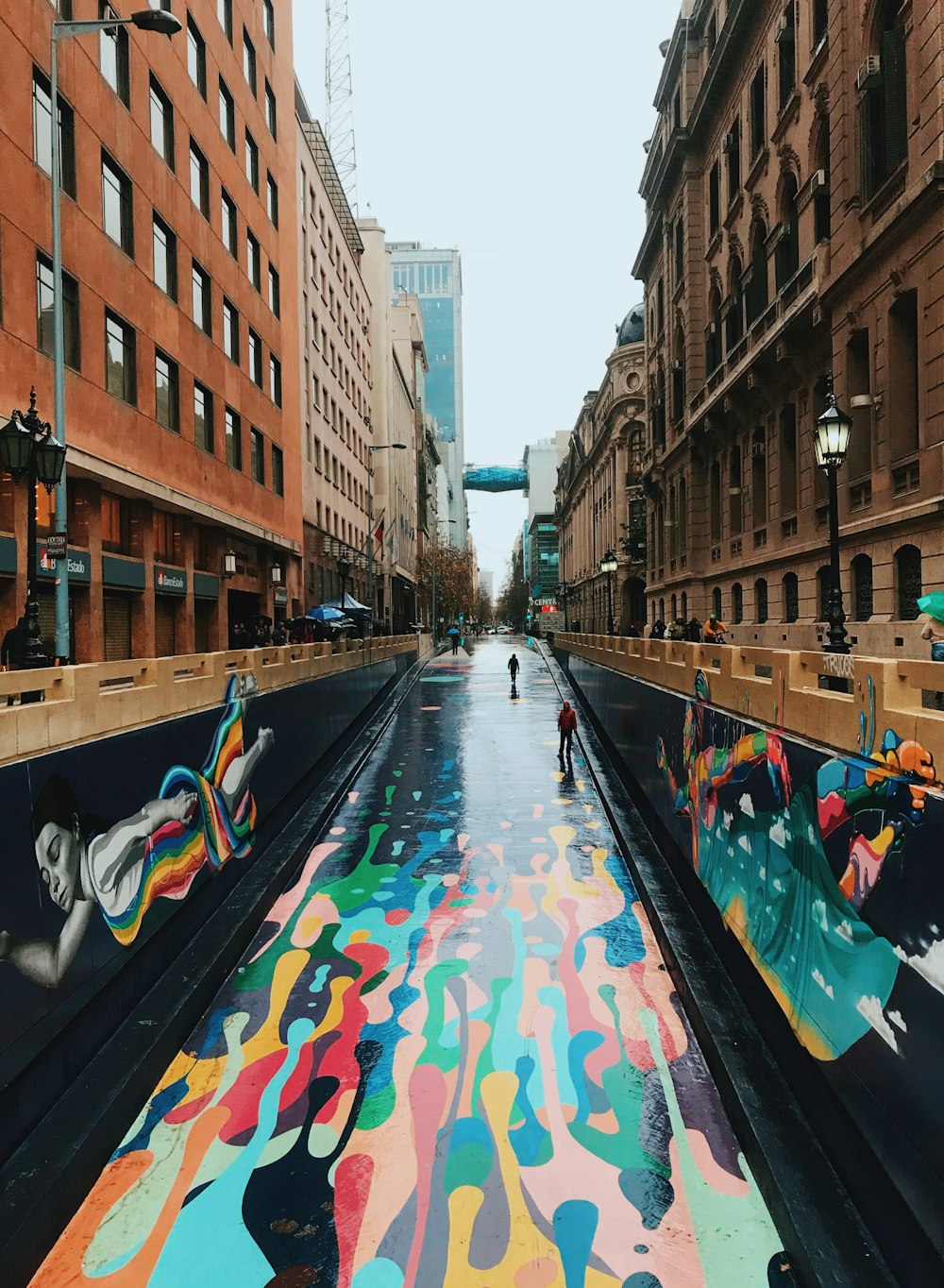 personas que viajan en un bote a motor azul y blanco en el río entre edificios de concreto marrón durante el día