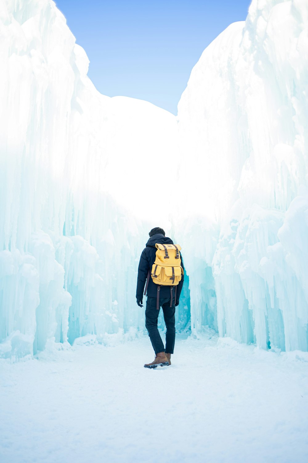 Mann in schwarzer Jacke und blauer Jeans auf schneebedecktem Boden