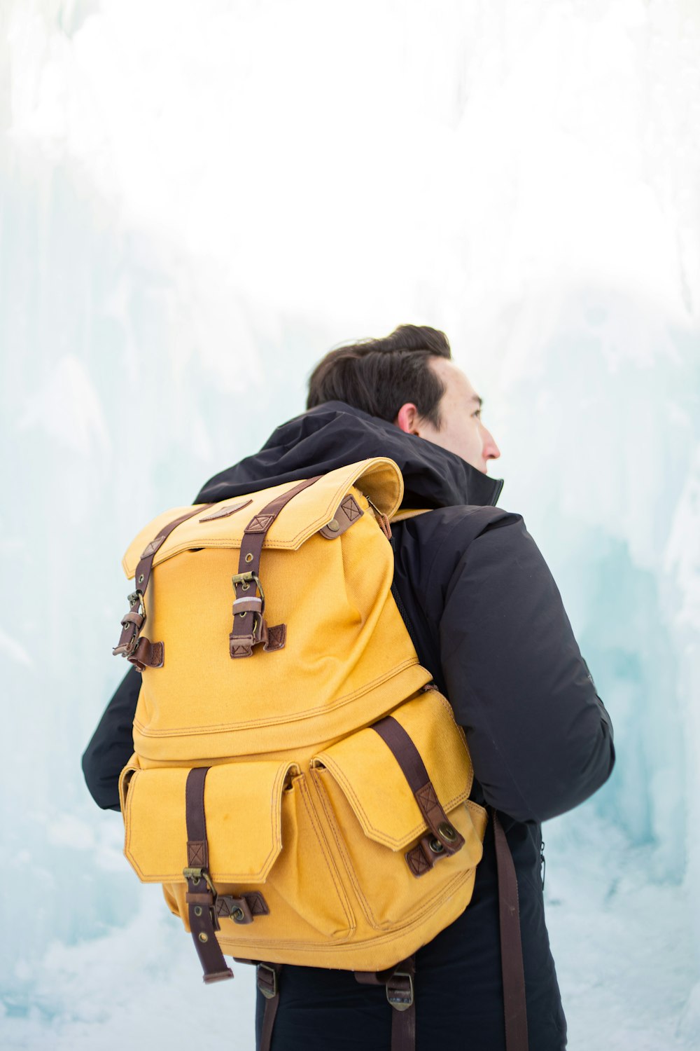 Mann in schwarzer Jacke und braunem Rucksack