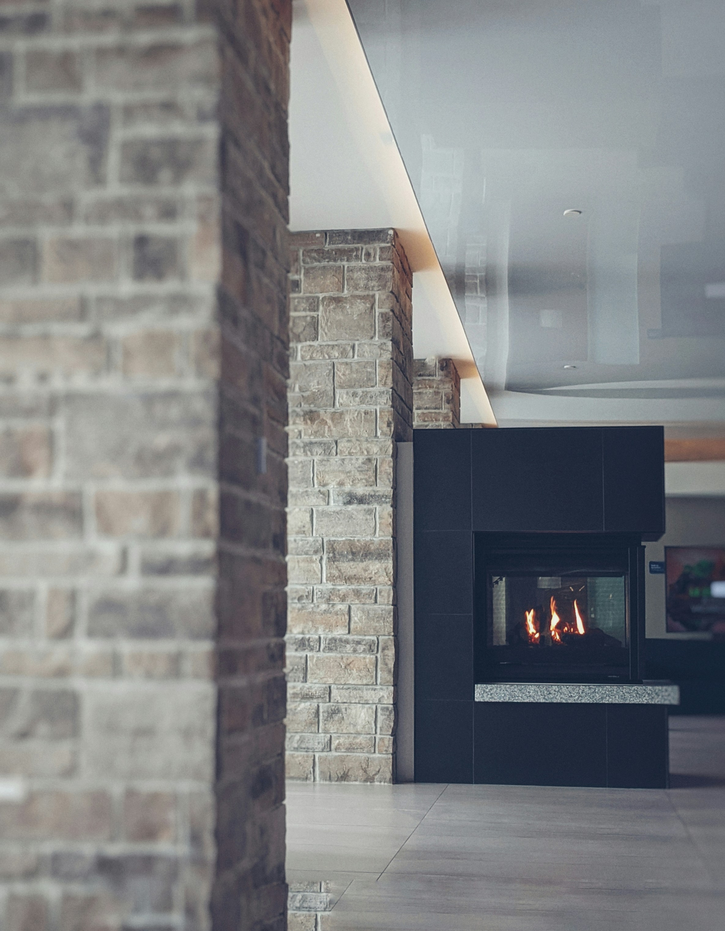 A modern interior featuring a stone wall and a sleek fireplace. The design includes a mix of rustic and contemporary elements with textured stone and smooth surfaces.