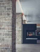 A modern interior featuring a stone wall and a sleek fireplace. The design includes a mix of rustic and contemporary elements with textured stone and smooth surfaces.