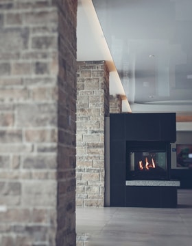 A modern interior featuring a stone wall and a sleek fireplace. The design includes a mix of rustic and contemporary elements with textured stone and smooth surfaces.