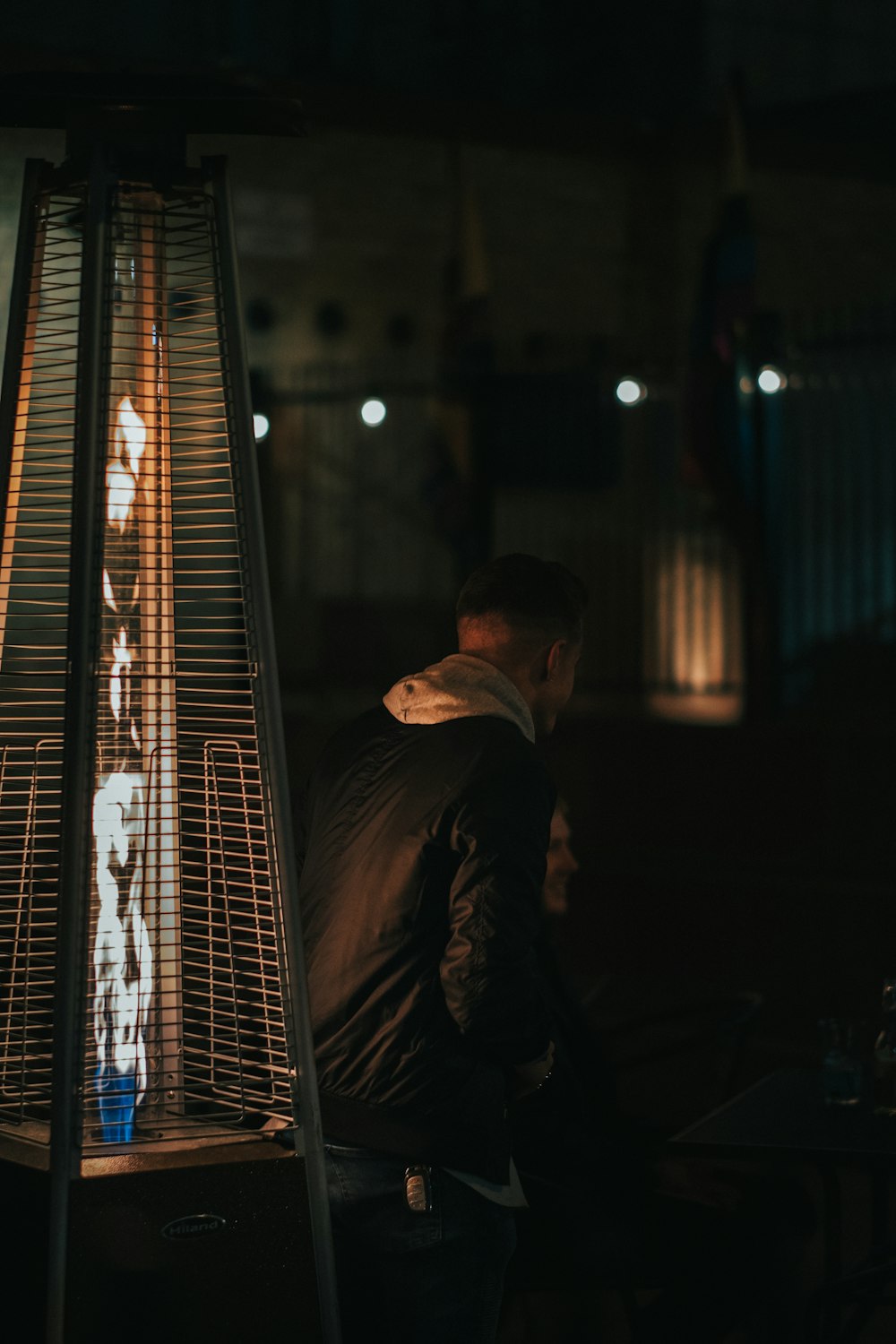 man in black jacket sitting beside window