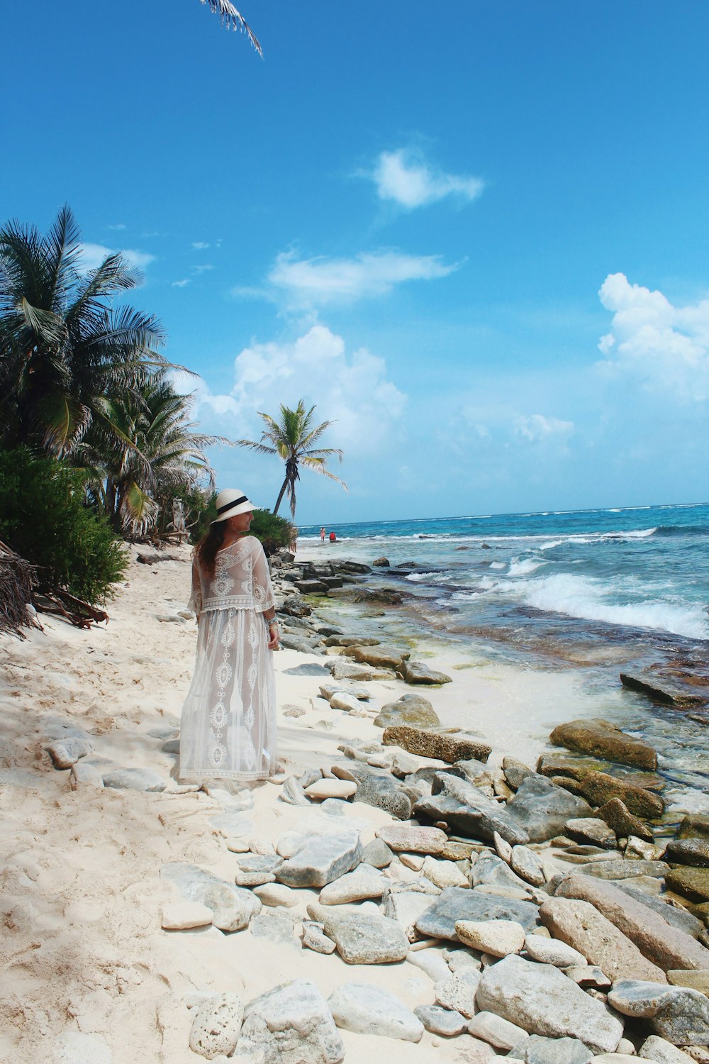 낮 동안 해변 해변에 서 있는 하얀 드레스를 입은 여자