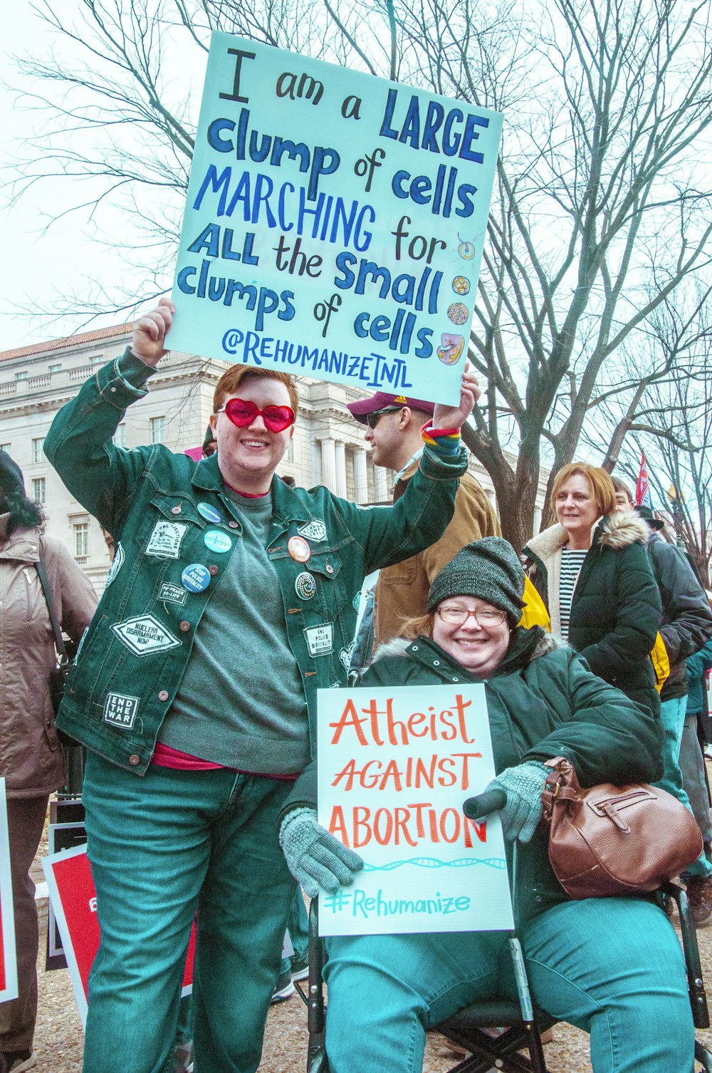 man in green jacket holding blue and white signage