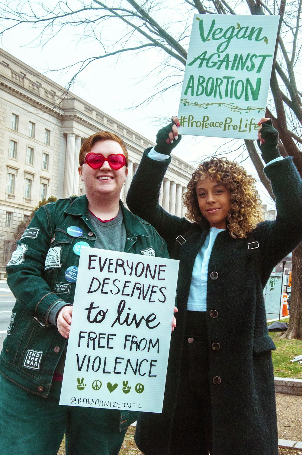 man in black coat holding white and green signage