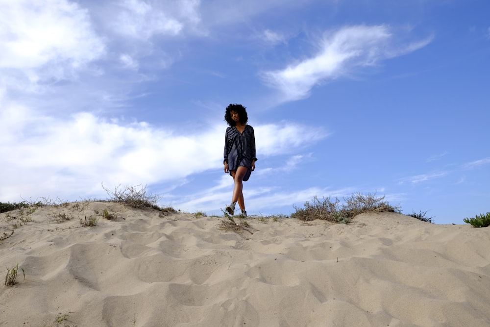 a woman standing on top of a sandy hill