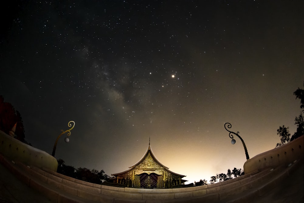 the night sky with stars and a building in the foreground