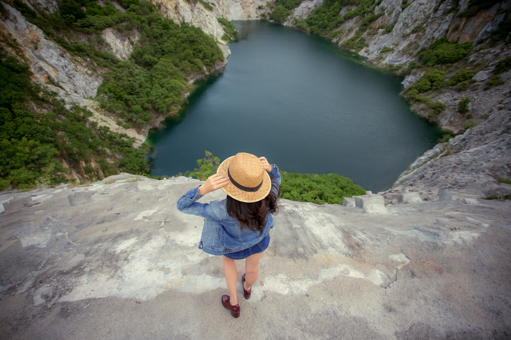 a woman wearing a hat standing on a cliff