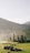 A serene landscape features a group of people gathered with tents and a vehicle on a green field. In the background, there are multi-tiered pagodas and lush mountainous terrain enveloped in a light mist, under a clear sky.