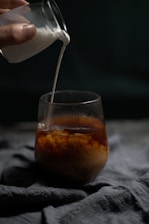 Fresh milk being poured into a glass from a traditional container.