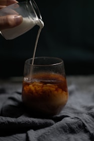 Fresh milk being poured into a glass from a traditional container.