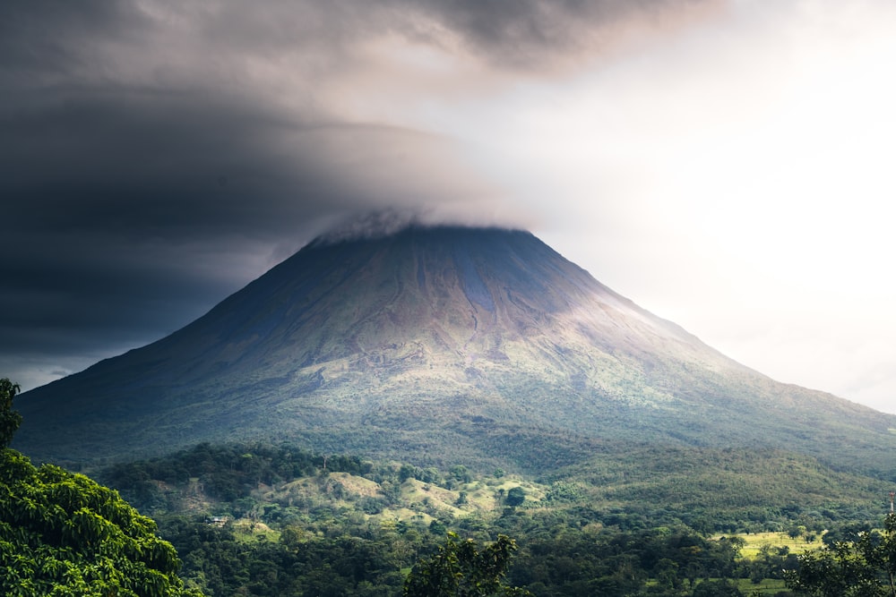 uma montanha muito alta com um céu muito nublado acima dela