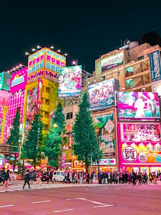 a group of people walking around a city at night