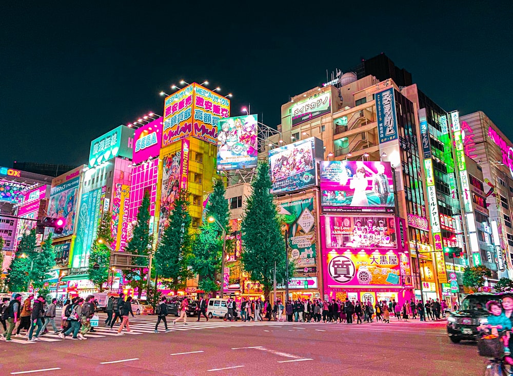 a group of people walking around a city at night