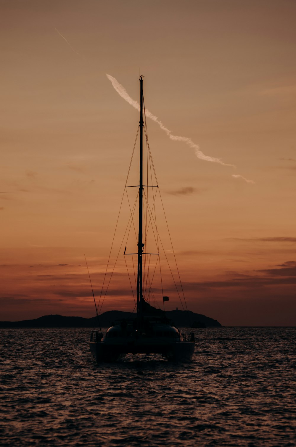 a sailboat in the water at sunset