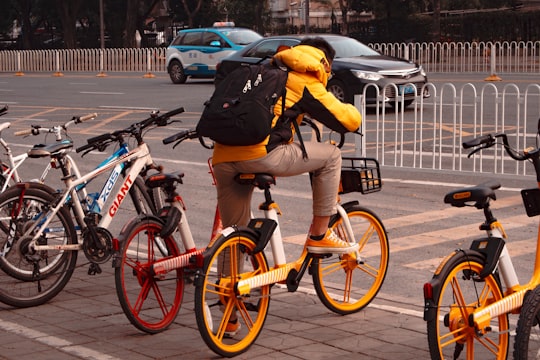 man in yellow jacket riding bicycle on road during daytime in Shenzhen China
