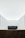 A minimalist interior space with stark white walls and ceiling. The room features a central dark-colored rectangular structure and another similar structure in the foreground. Subtle architectural details and lighting create a serene and spacious atmosphere.