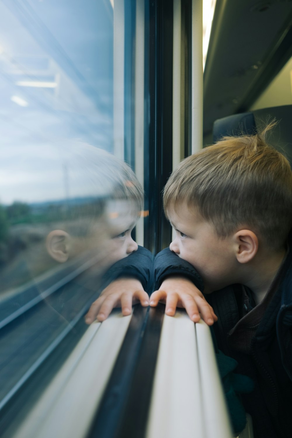 two young boys looking out the window of a train
