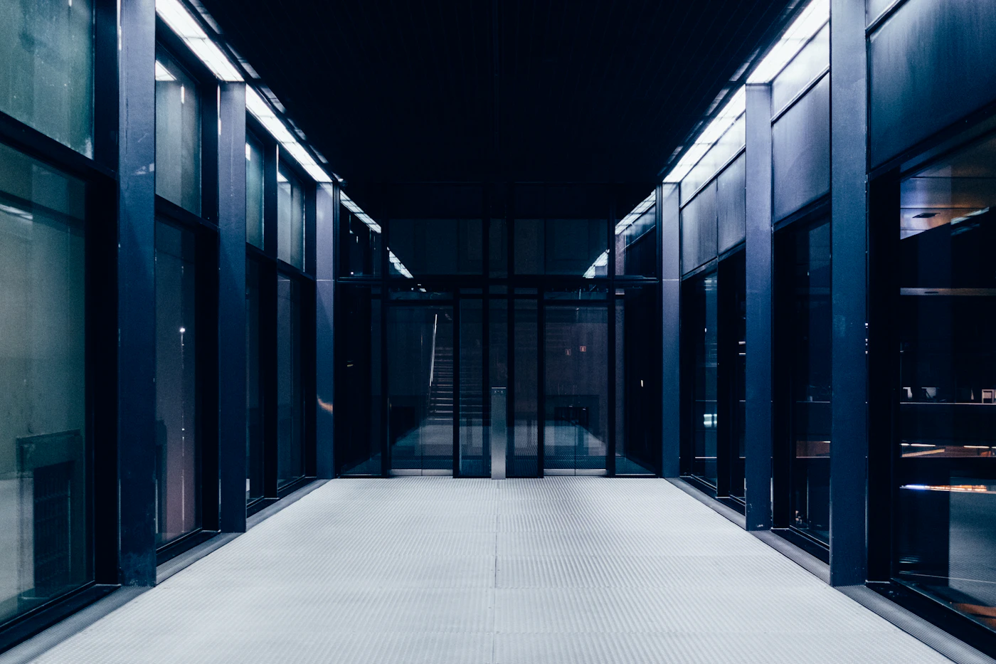 Clean data center corridor with glass-panel racks extending to vanishing point