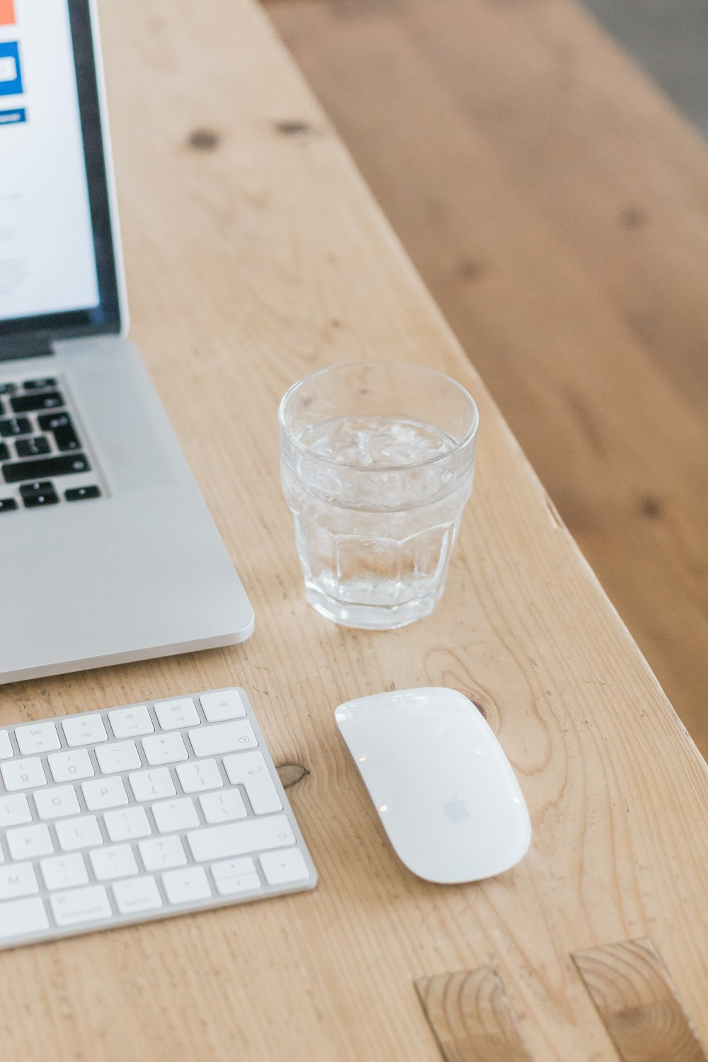 clear drinking glass beside white apple magic mouse on brown wooden table