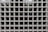 A grid of square glass blocks, each framed by white borders. The glass blocks are translucent with a textured surface, creating a pattern of reflections and refractions. The overall appearance is uniform and geometric, with a modern architectural style.