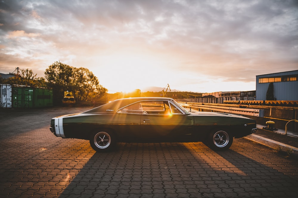 black coupe parked on brown brick floor during sunset