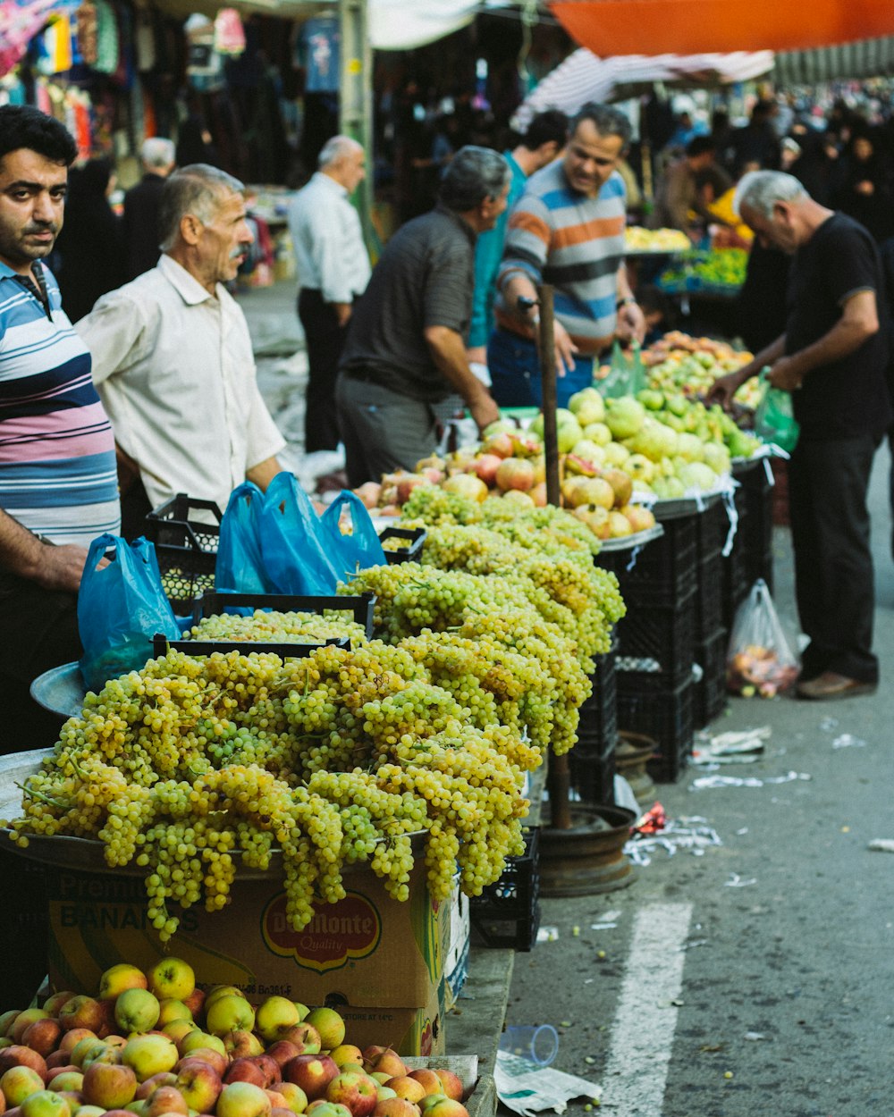 a group of people standing around a table filled with fruit