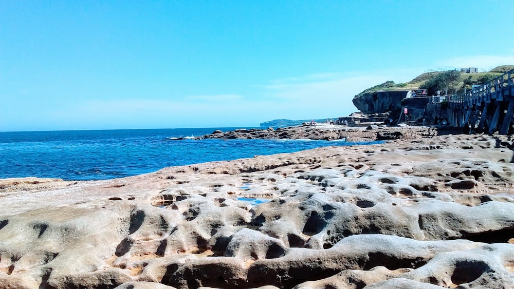 a rocky beach with a body of water in the background