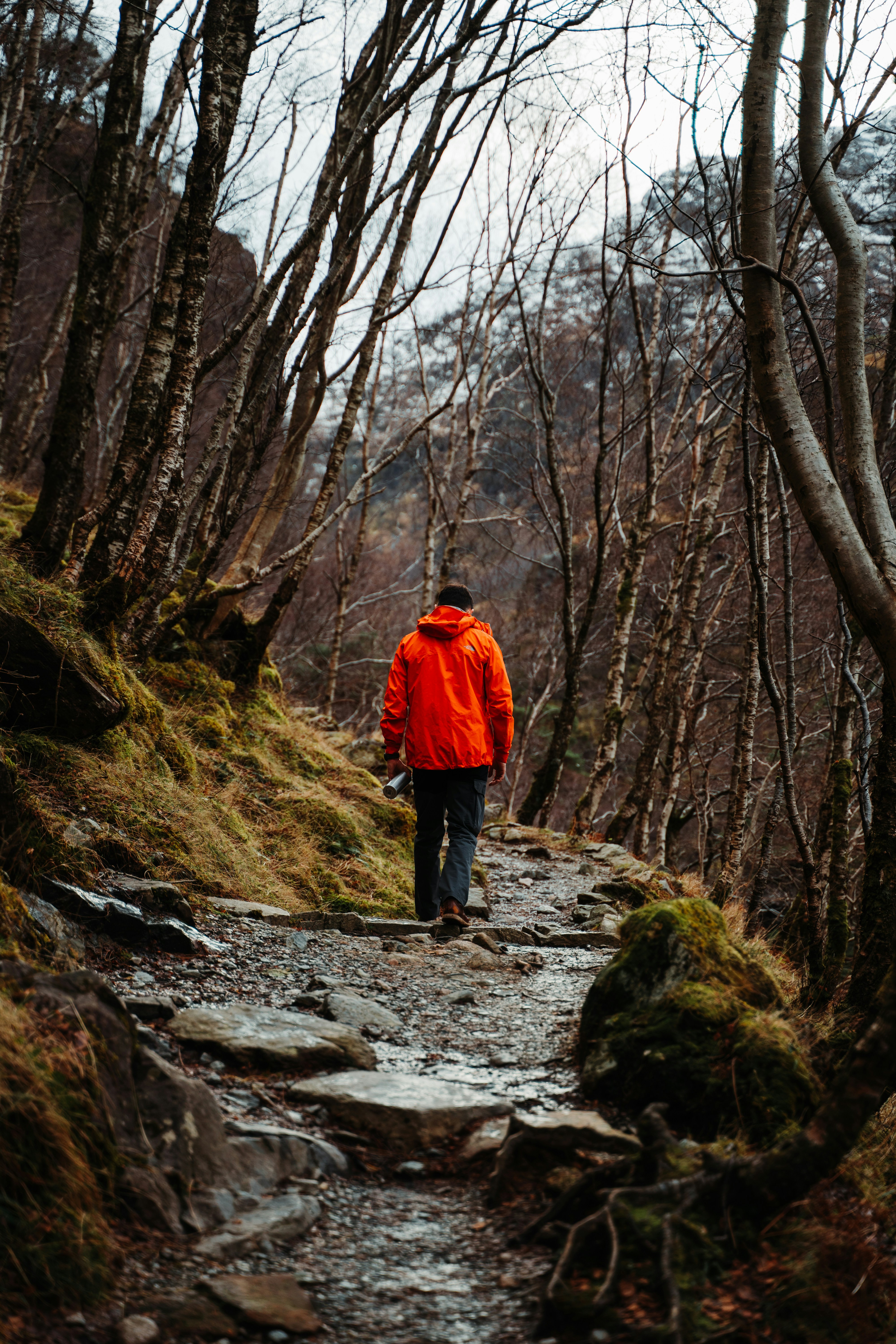 a man in an orange jacket walking down a trail