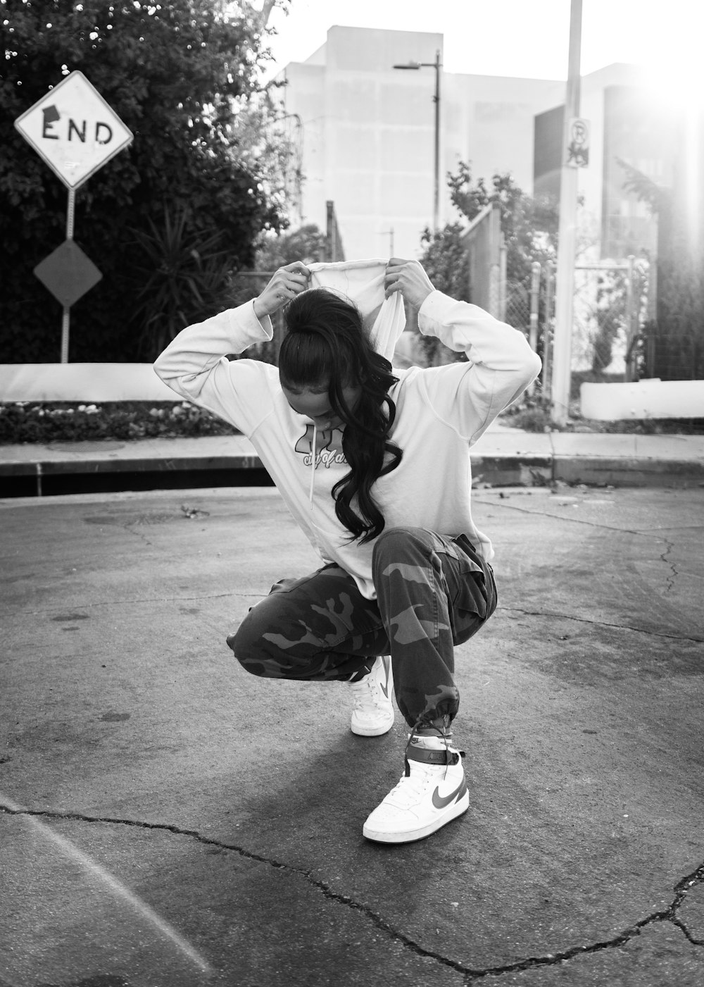 a woman squatting on the ground with her hands behind her head