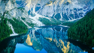 a mountain lake surrounded by trees and snow
