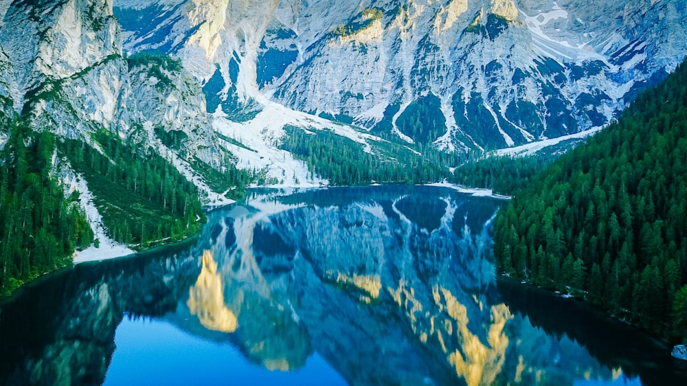 um lago de montanha cercado por árvores e neve