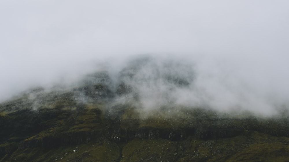 a mountain covered in fog and clouds on a cloudy day