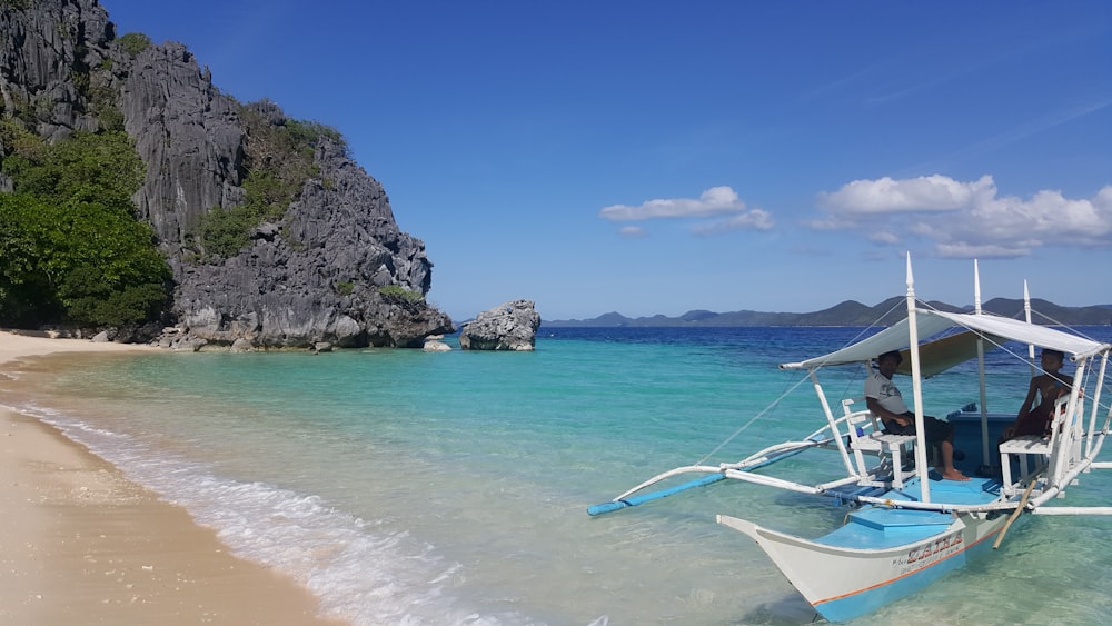 white and blue boat on beach during daytime