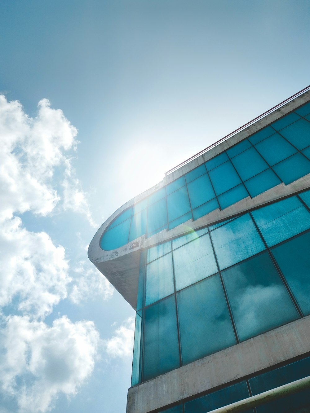 blue glass walled building under white clouds and blue sky during daytime