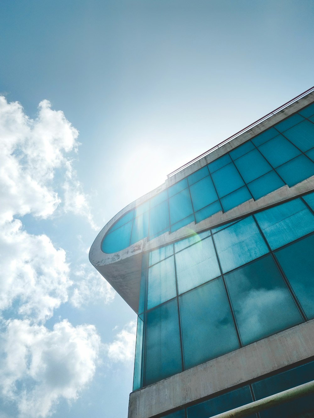 bâtiment aux murs de verre bleu sous les nuages blancs et le ciel bleu pendant la journée