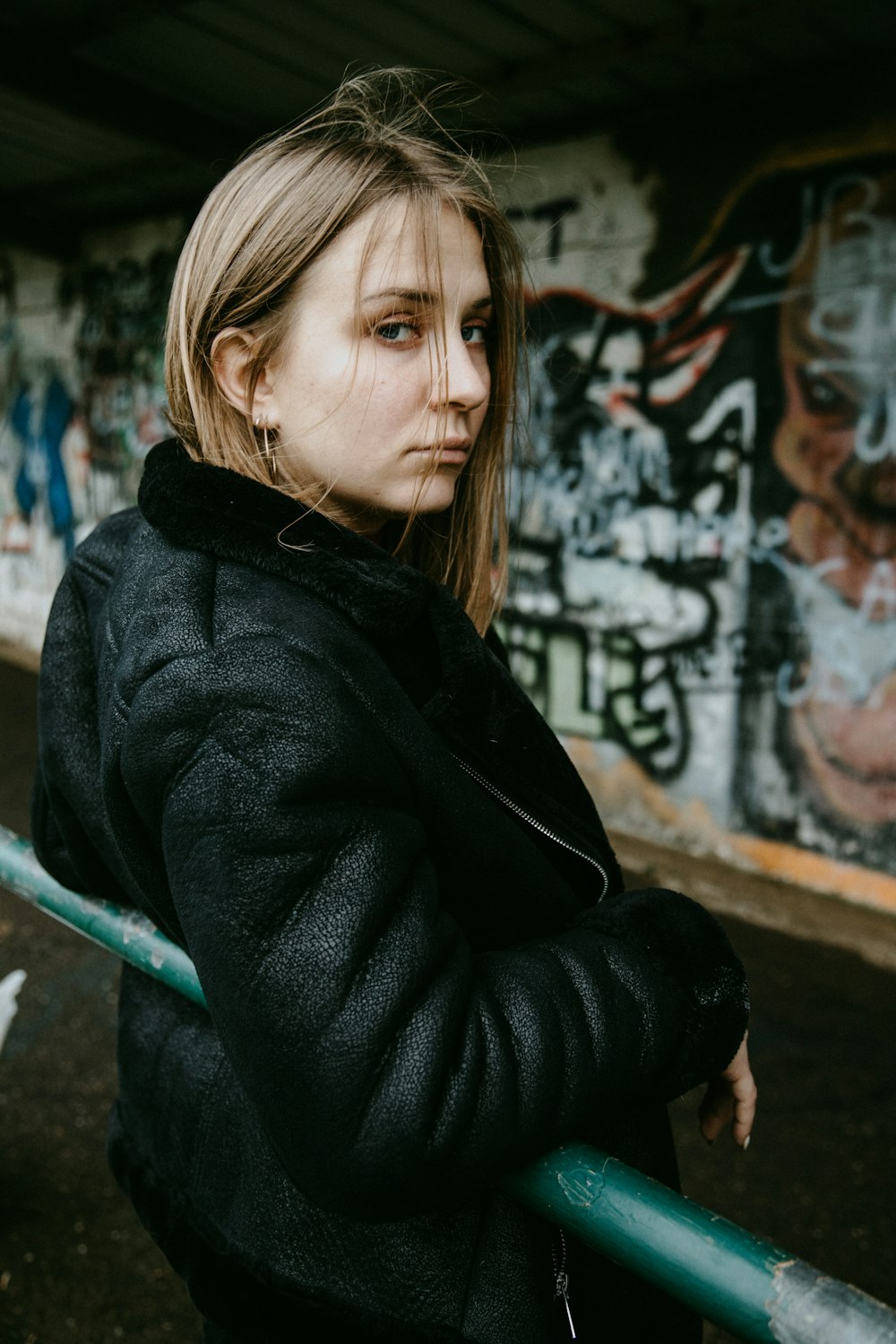 woman in black coat sitting on brown wooden bench