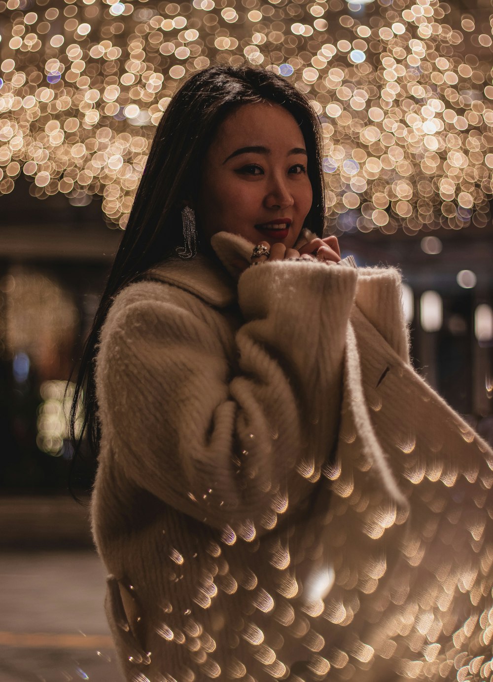 woman in brown coat holding lighted string lights