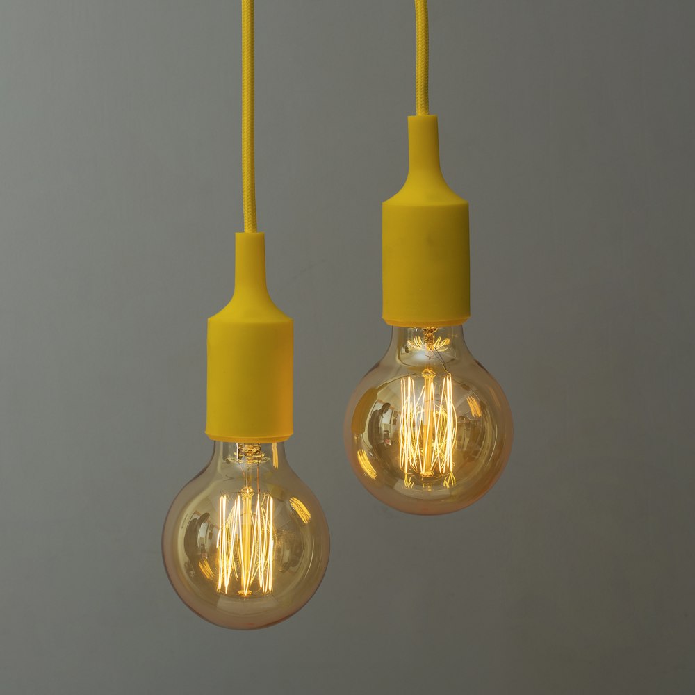 a couple of yellow light bulbs hanging from a ceiling