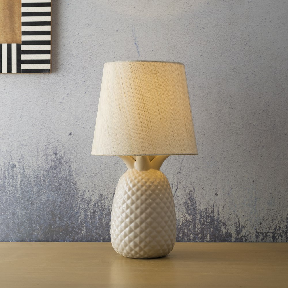 una lampada da tavolo bianca seduta sopra un tavolo di legno