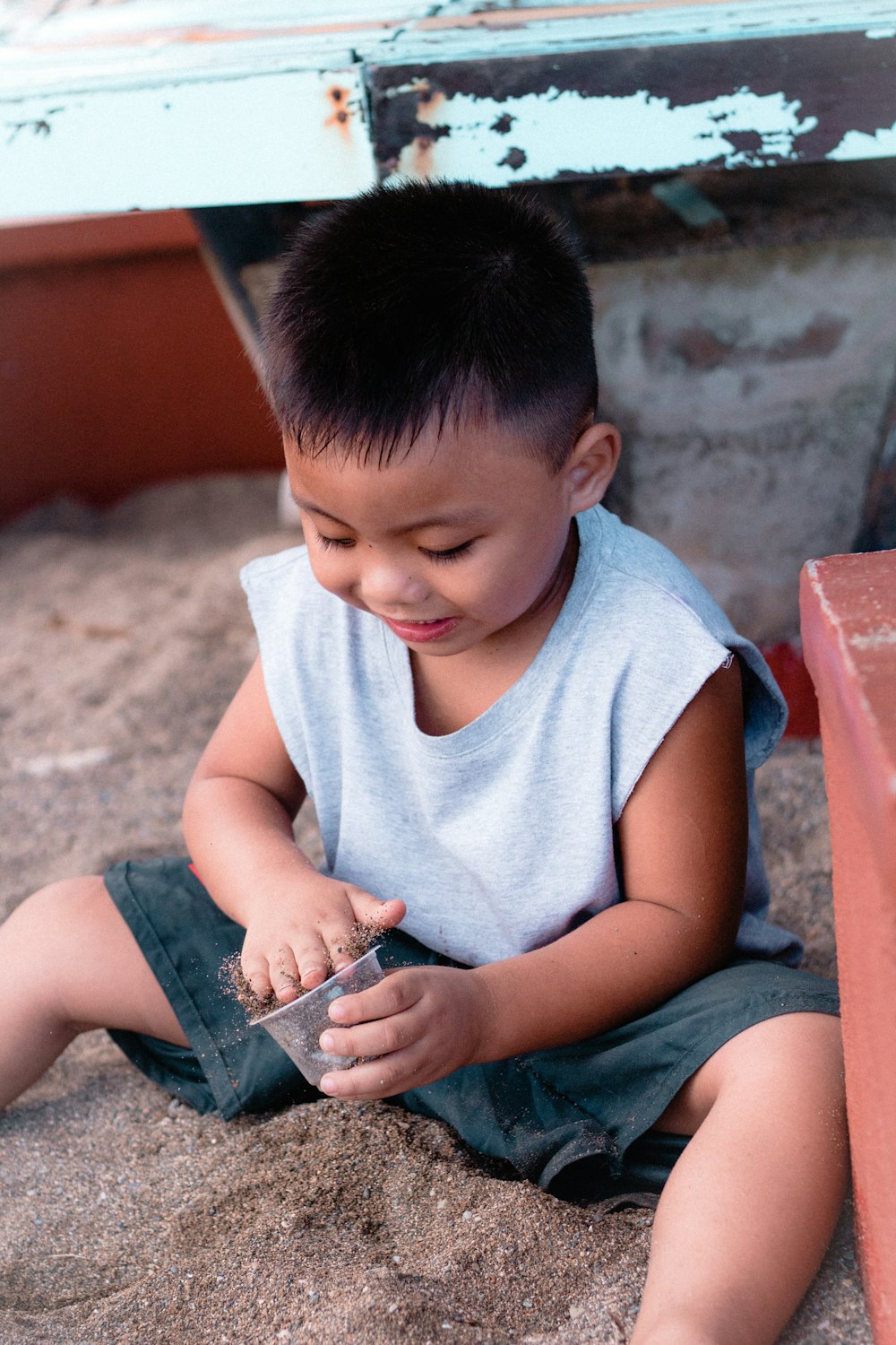 a little boy sitting on the ground playing with a cell phone