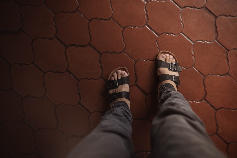 une personne portant des sandales debout sur un sol carrelé